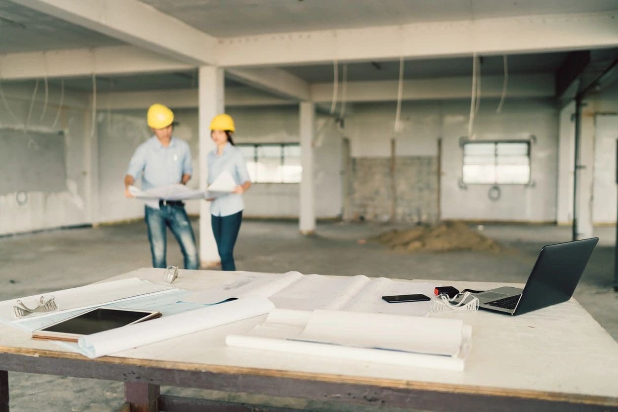 Two people in hard hats standing next to a table.